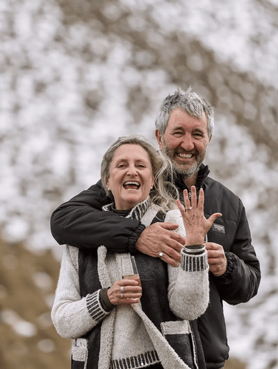 Happy couple celebrating engagement, woman showing diamond ring outdoors in winter